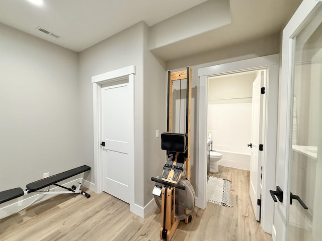 exercise area featuring light wood-type flooring, visible vents, and baseboards