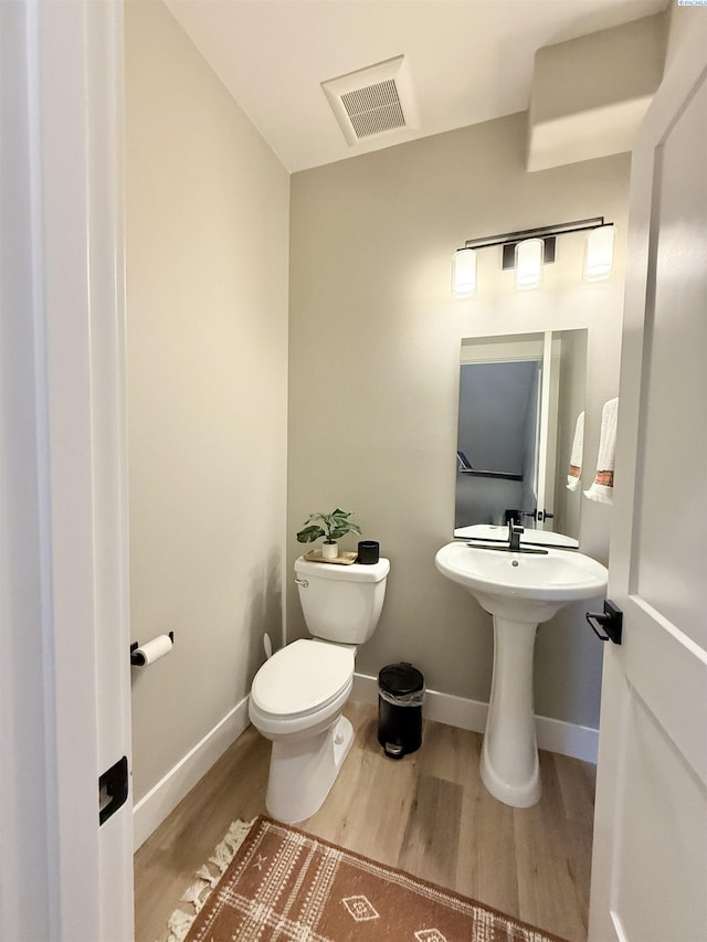 bathroom featuring toilet, baseboards, visible vents, and wood finished floors