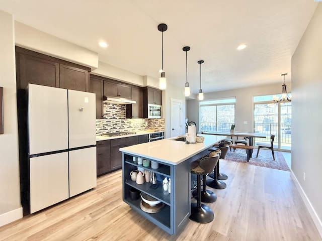 kitchen with open shelves, stainless steel appliances, tasteful backsplash, light countertops, and dark brown cabinetry