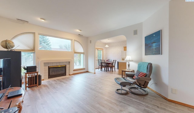 living area with a tile fireplace and light hardwood / wood-style floors