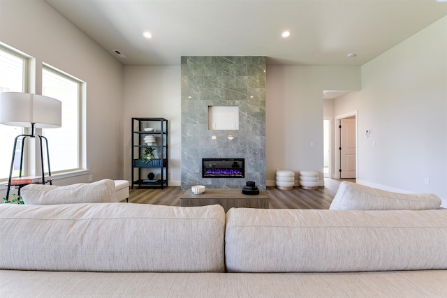 living area featuring baseboards, a tiled fireplace, wood finished floors, and recessed lighting