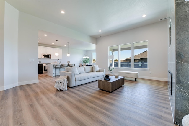 living area featuring baseboards, light wood-style flooring, and recessed lighting