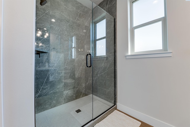 bathroom with baseboards, a marble finish shower, and wood finished floors