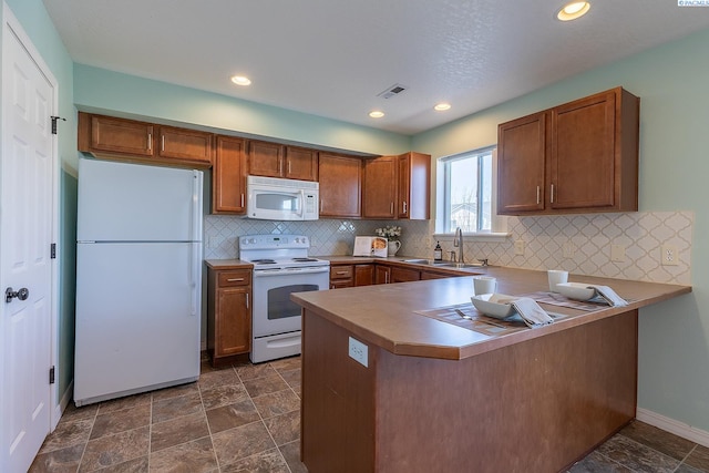 kitchen with visible vents, a peninsula, brown cabinets, and white appliances