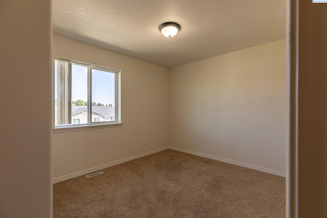 unfurnished room with carpet floors, baseboards, a textured ceiling, and visible vents