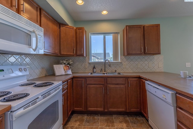 kitchen with brown cabinets, a sink, white appliances, recessed lighting, and tasteful backsplash