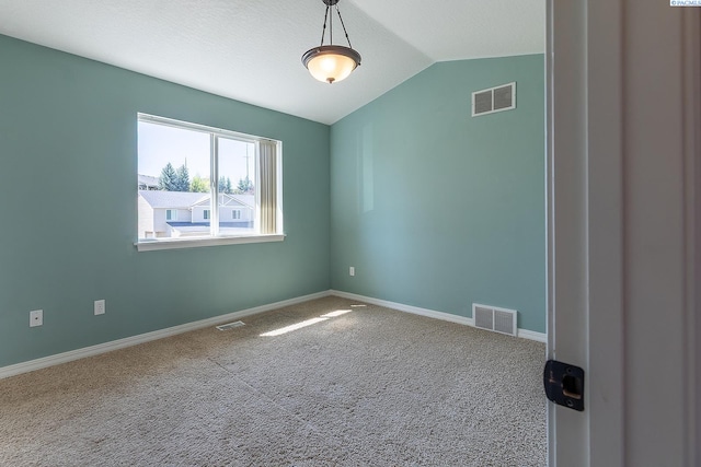 carpeted empty room with baseboards, vaulted ceiling, and visible vents
