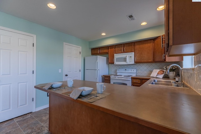 kitchen featuring brown cabinets, a sink, white appliances, decorative backsplash, and visible vents