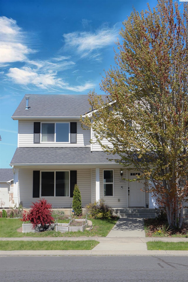 view of front of property featuring a front lawn and roof with shingles