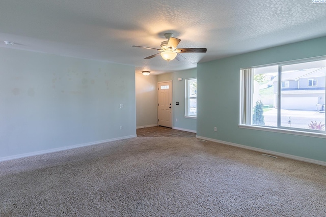 carpeted empty room featuring visible vents, a ceiling fan, a textured ceiling, and baseboards