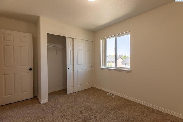 unfurnished bedroom featuring visible vents, carpet, baseboards, and a closet