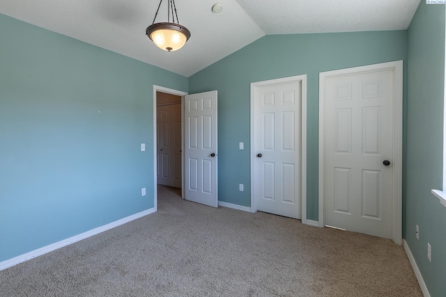 unfurnished bedroom featuring carpet floors, baseboards, and vaulted ceiling