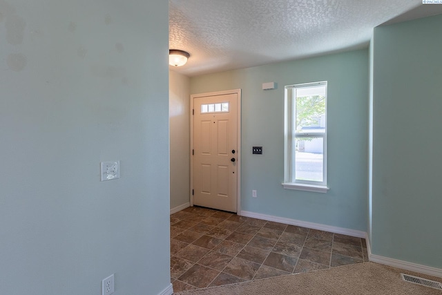 entrance foyer featuring baseboards, a textured ceiling, and visible vents