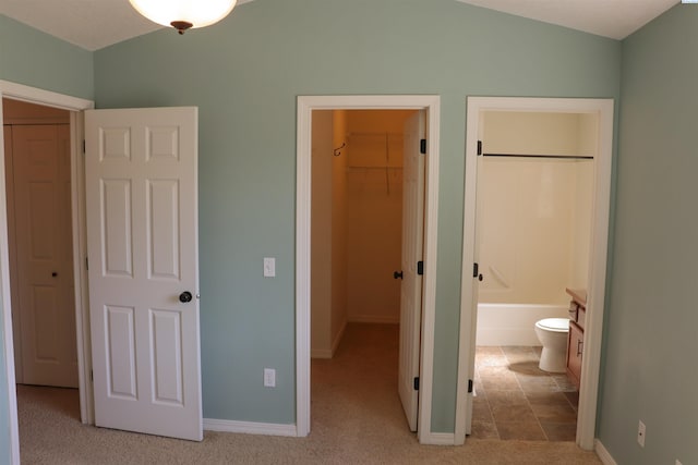unfurnished bedroom with a walk in closet, baseboards, a closet, and carpet floors