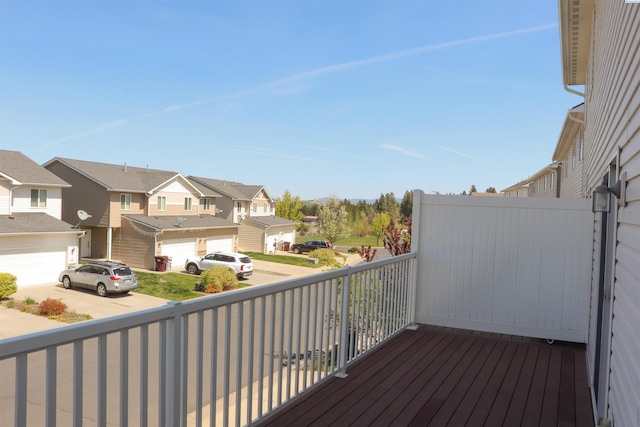 wooden terrace featuring a garage, driveway, and a residential view