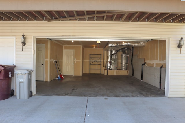 garage featuring heating unit, strapped water heater, and concrete driveway