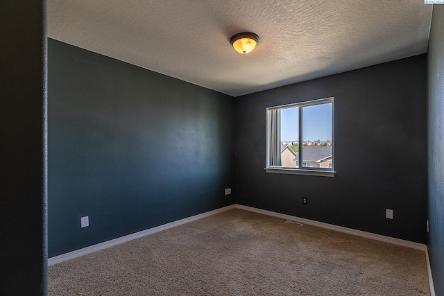 unfurnished room with baseboards, carpet flooring, a textured ceiling, and visible vents