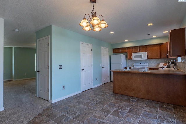kitchen with brown cabinetry, a peninsula, white appliances, baseboards, and a sink
