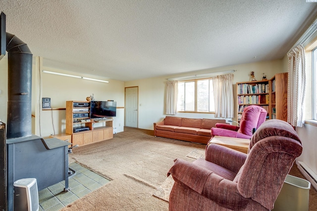 carpeted living room with a wood stove, a baseboard radiator, and a textured ceiling