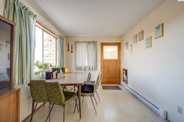 dining room with plenty of natural light, baseboard heating, and a textured ceiling