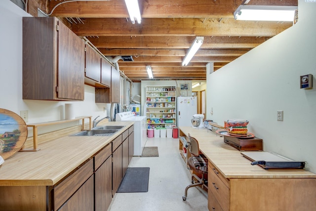 kitchen with a sink, concrete floors, light countertops, and washer and dryer