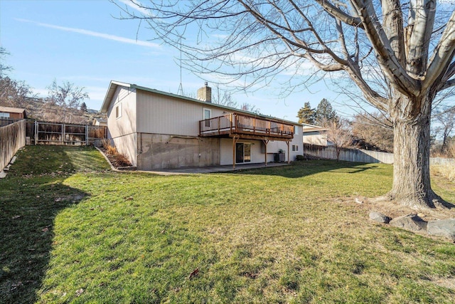 back of house with a deck, a yard, a chimney, and a fenced backyard