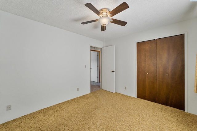 unfurnished bedroom with a ceiling fan, carpet, a closet, and a textured ceiling