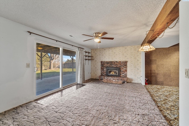 unfurnished living room featuring carpet, a ceiling fan, a brick fireplace, a textured ceiling, and wallpapered walls