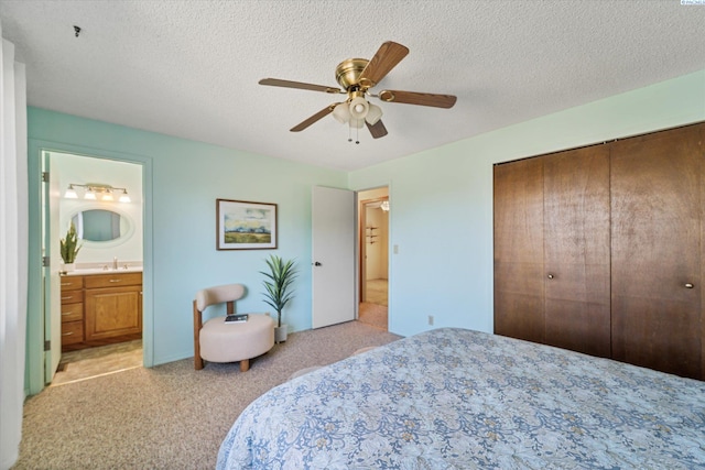 bedroom with a closet, a textured ceiling, a sink, and light colored carpet