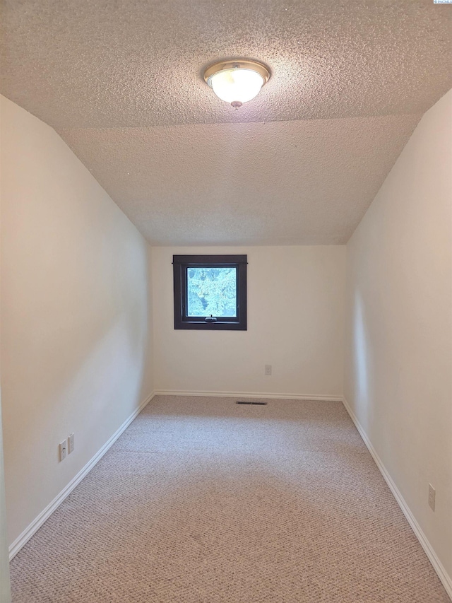 6302 Sand Rd, Pullman, WA 99163 - unfurnished room featuring a textured ceiling, light carpet, vaulted ceiling, and baseboards