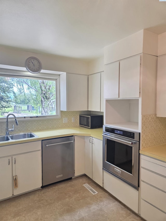 6302 Sand Rd, Pullman, WA 99163 - kitchen with appliances with stainless steel finishes, a sink, tasteful backsplash, light countertops, and white cabinetry