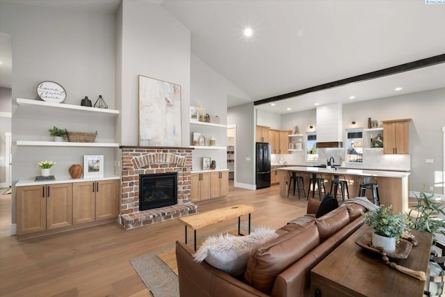 4402 Everett St, West Richland, WA 99353 - living room featuring high vaulted ceiling, sink, light hardwood / wood-style floors, and a brick fireplace