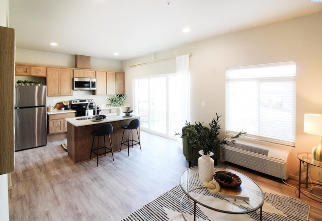 1200 N 8th Ave Unit A204, Othello, WA 99327 - kitchen with stainless steel appliances, light wood-type flooring, light brown cabinetry, a kitchen bar, and a center island with sink