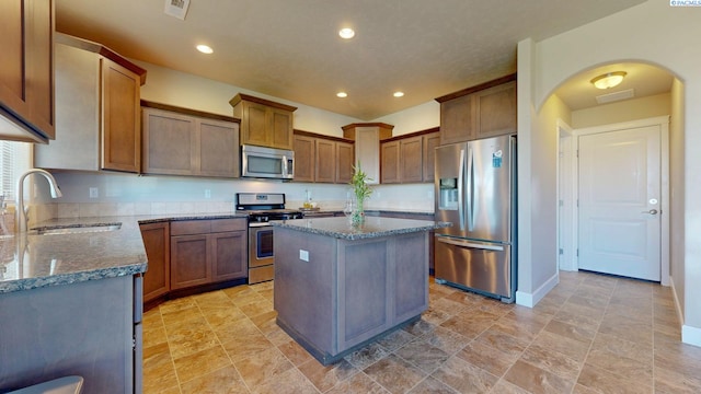 5802 Sidon Ln, Pasco, WA 99301 - kitchen with stainless steel appliances, dark stone countertops, a kitchen island, arched walkways, and recessed lighting
