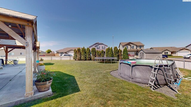 5802 Sidon Ln, Pasco, WA 99301 - fenced backyard with a trampoline, a shed, a residential view, and a patio area