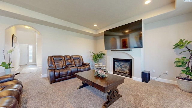 5802 Sidon Ln, Pasco, WA 99301 - carpeted living room featuring arched walkways, a raised ceiling, recessed lighting, and a glass covered fireplace