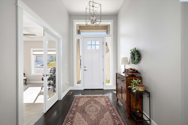 entrance foyer with dark wood-style floors, visible vents, a wealth of natural light, and baseboards