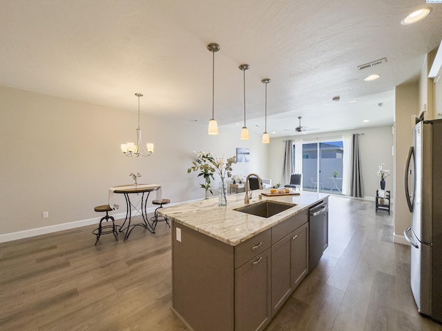 kitchen with dark wood-style floors, stainless steel appliances, a sink, and a center island with sink