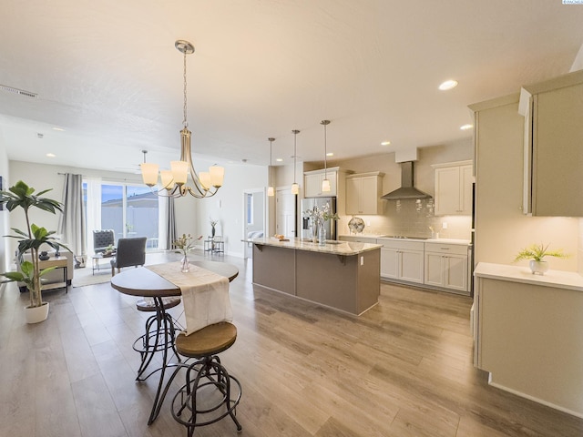 kitchen with stainless steel fridge, light wood-style flooring, wall chimney exhaust hood, and black electric cooktop