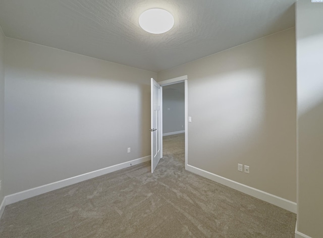 empty room featuring a textured ceiling, carpet floors, and baseboards