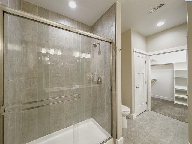 bathroom featuring a stall shower, a walk in closet, visible vents, and toilet