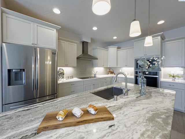 kitchen with decorative backsplash, wall chimney exhaust hood, hanging light fixtures, black appliances, and a sink