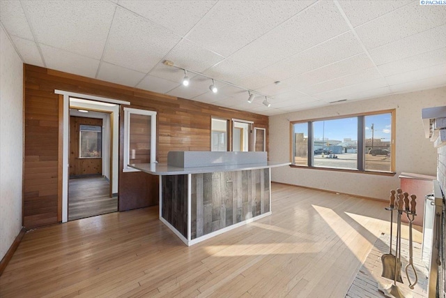 kitchen with wooden walls, baseboards, light countertops, light wood-type flooring, and track lighting