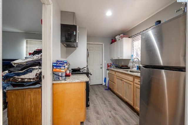 kitchen featuring light wood-style flooring, a sink, and freestanding refrigerator