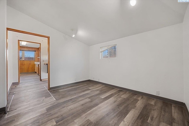 spare room with lofted ceiling, wood finished floors, and baseboards