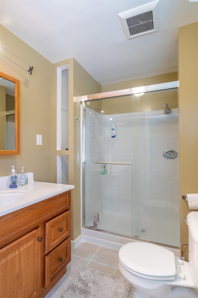 bathroom featuring tile patterned flooring, vanity, walk in shower, and toilet