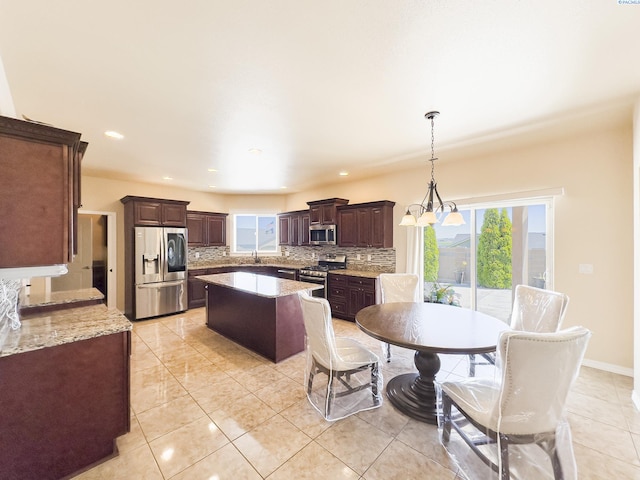 4807 Adobe Dr, Pasco, WA 99301 - kitchen with stainless steel appliances, decorative backsplash, a center island, dark brown cabinets, and light tile patterned floors