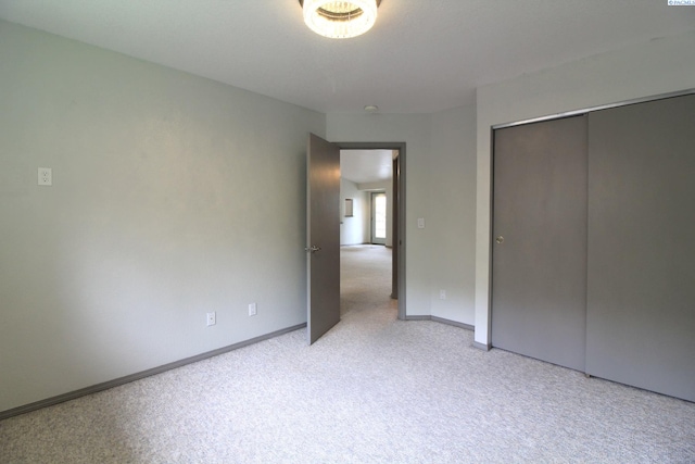 unfurnished bedroom with a closet, baseboards, and light carpet