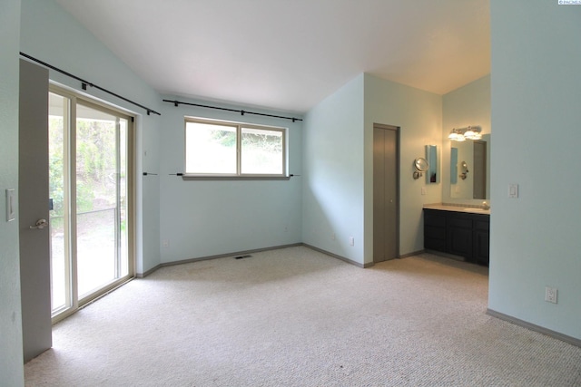 unfurnished bedroom featuring access to outside, light colored carpet, baseboards, and ensuite bathroom