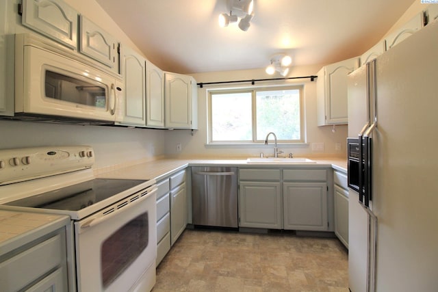 kitchen with tile counters, white appliances, gray cabinetry, stone finish floor, and a sink